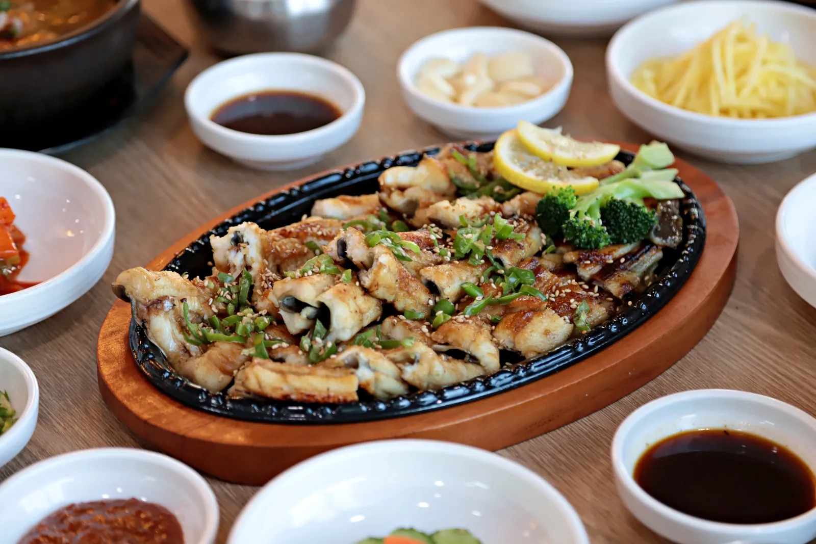 철판 위에 올린 장어구이 야끼바, 청양고추와 깨, 레몬을 곁들인 모습